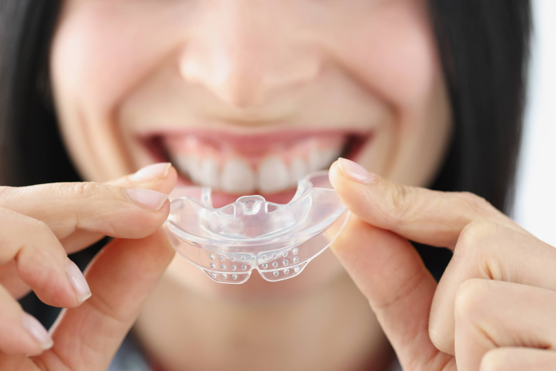 Smiling woman holding plastic mouth guard for teeth whitening