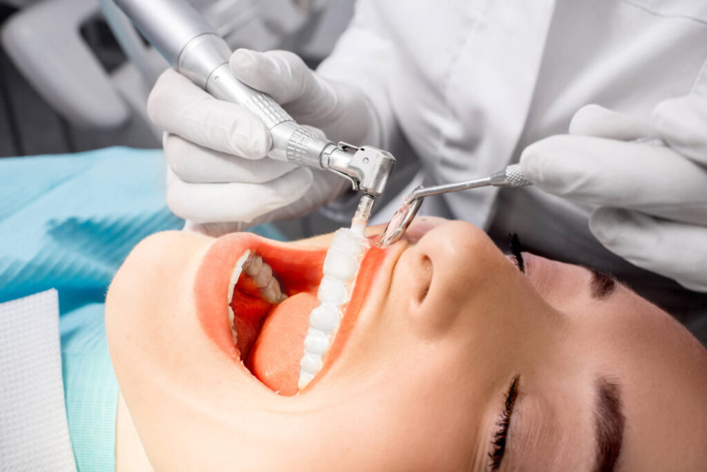 Dentist making professional teeth cleaning female young patient