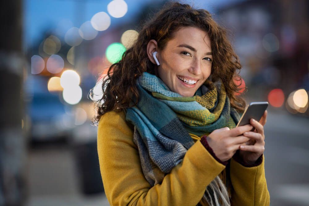 Young beautiful woman using mobile phone at dusk in the city