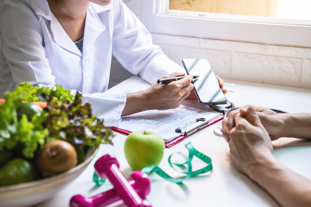 Nutritionist giving consultation to patient with healthy fruit and vegetable