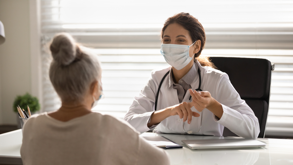 Female doctor in medical facial mask have consultation with elderly patient