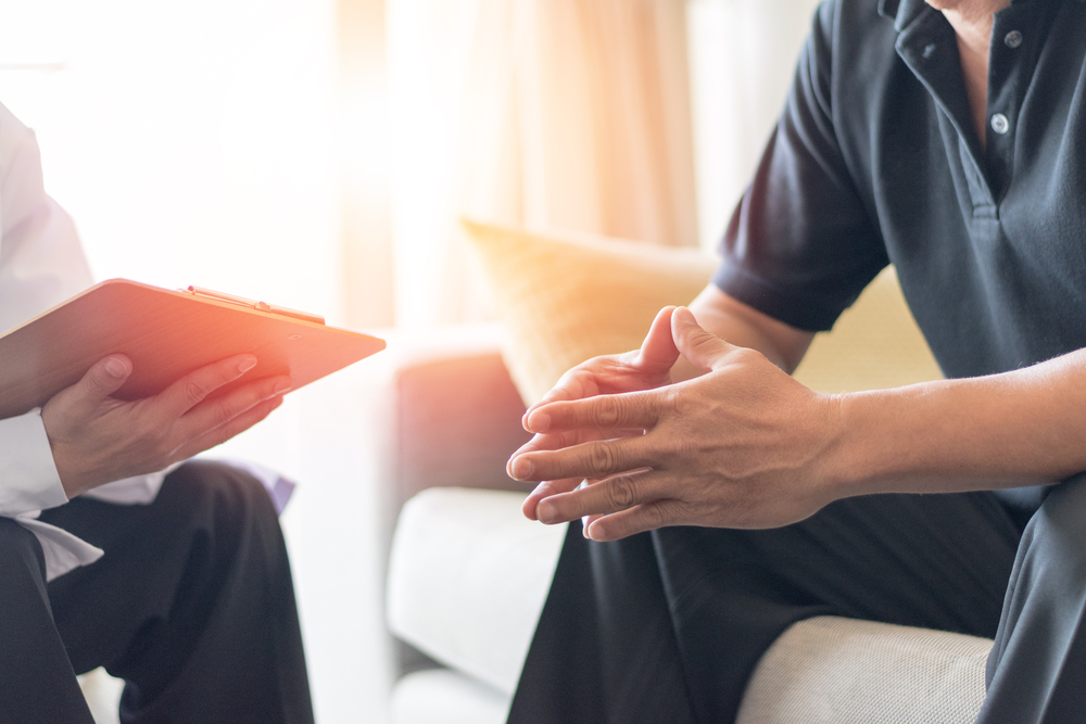 Doctor physician consulting with male patients in hospital exam room