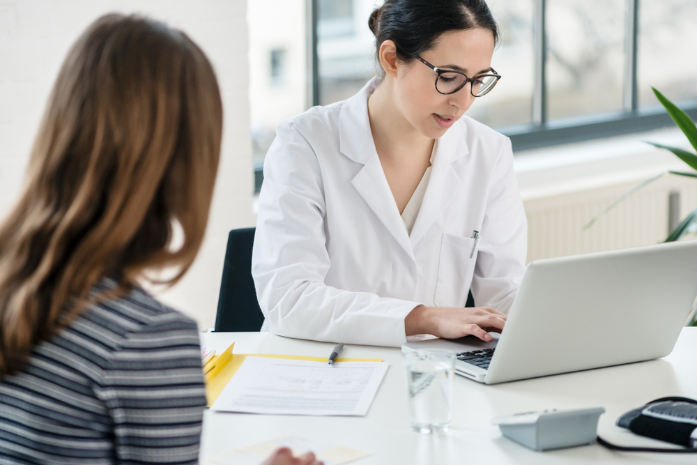 Primary care physician typing on laptop useful observations while listening to her female patient