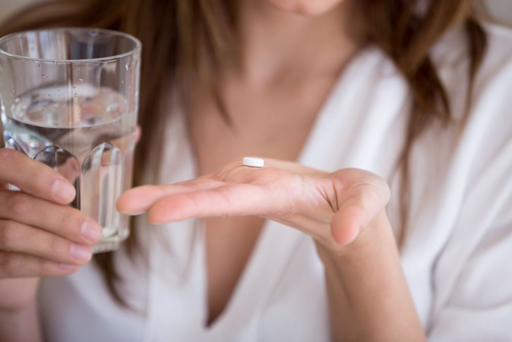 Woman hand holding contraceptive pills and Water