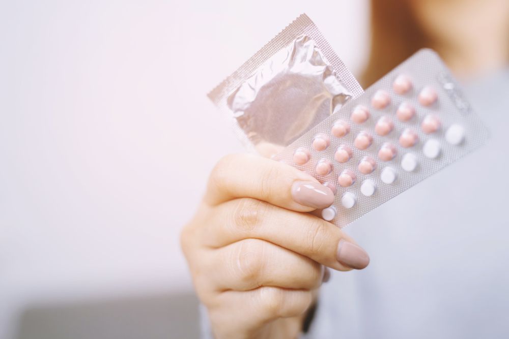 Woman hand holding contraceptive pills and condom