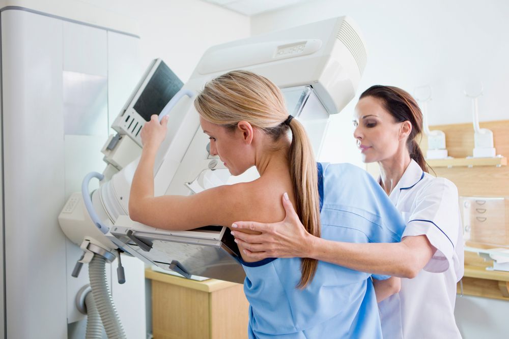 Nurse preparing a patient for a mammogram at x-ray machine in the hospital