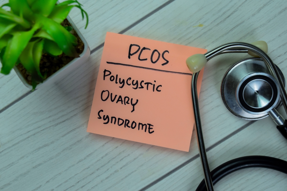 Concept of POCS Polycystic Ovary Syndrome write on sticky notes with stethoscope isolated on Wooden Table.