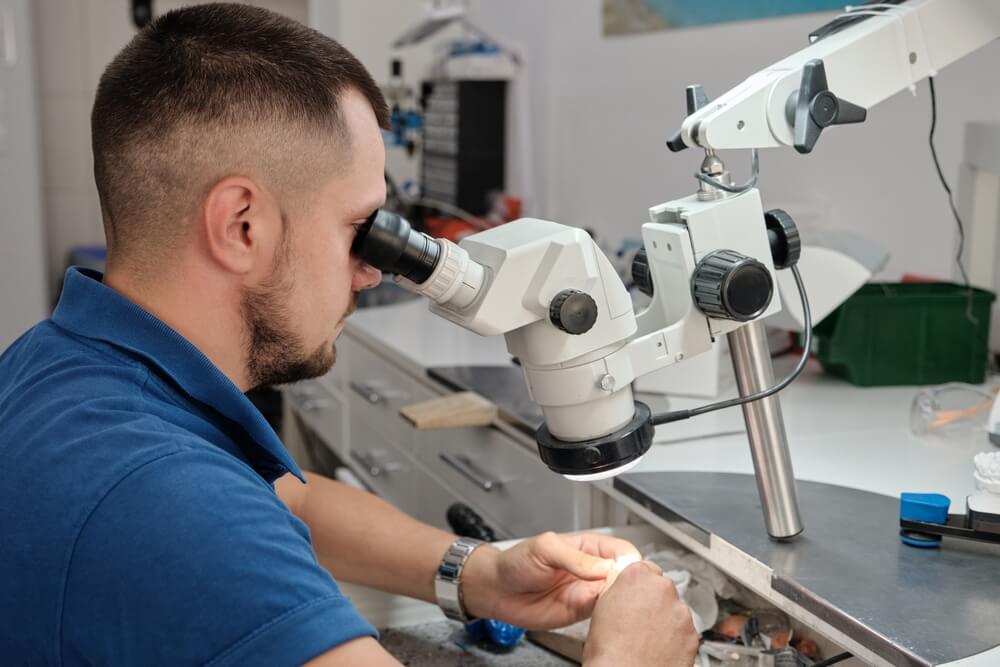 Technician in dental lab working under a microscope