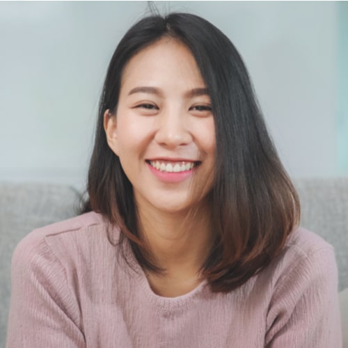 Teenager Asian woman feeling happy smiling and looking to camera while relax in living room at home.