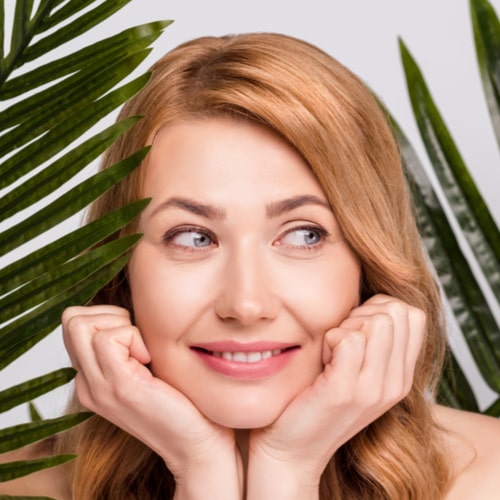 Portrait of attractive woman with leaves thinking facial product