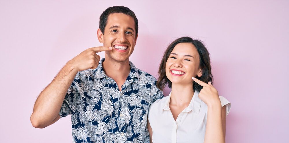 Beautiful couple wearing casual clothes smiling cheerful showing and pointing with fingers teeth