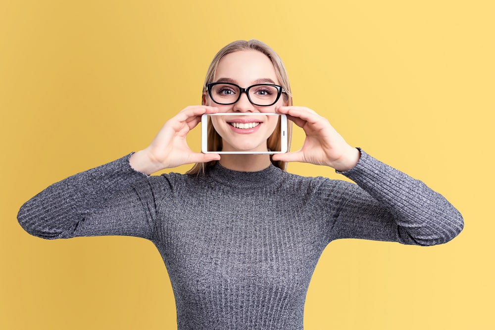 teen girl taking self picture of her smile with smartphone