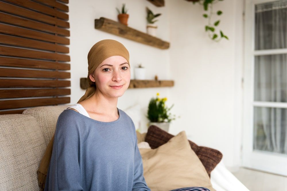 young positive adult female cancer patient sitting in living room