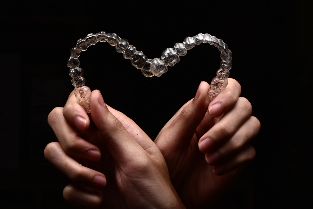 Invisalign,Closeup,Heart,Shape,In,Hands,Black,Background