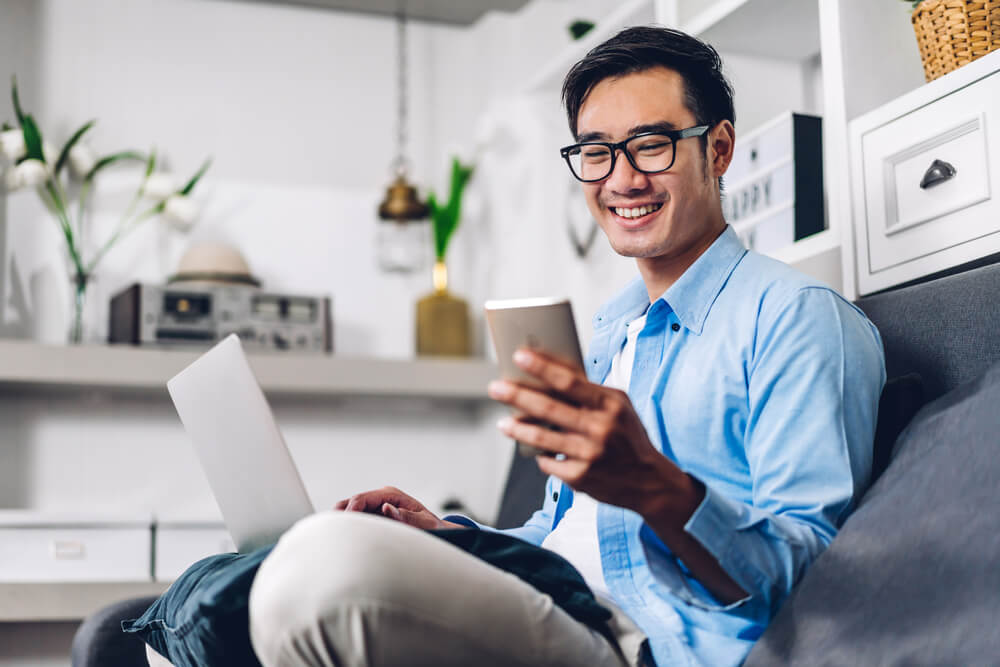 Young smiling asian man relaxing using laptop computer