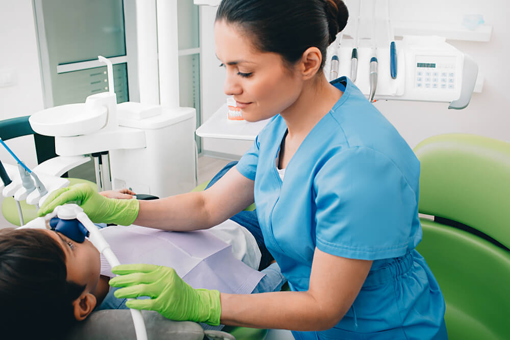 Pediatric dentist doing Inhalation Sedation to a child while teeth treatment at dental clinic.