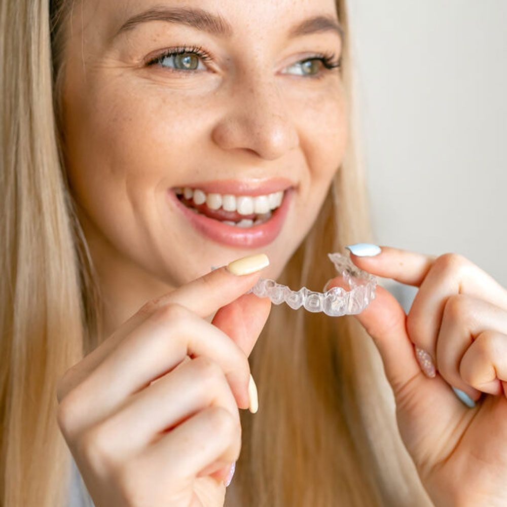 Smiling woman with healthy teeth using removable clear braces aligner