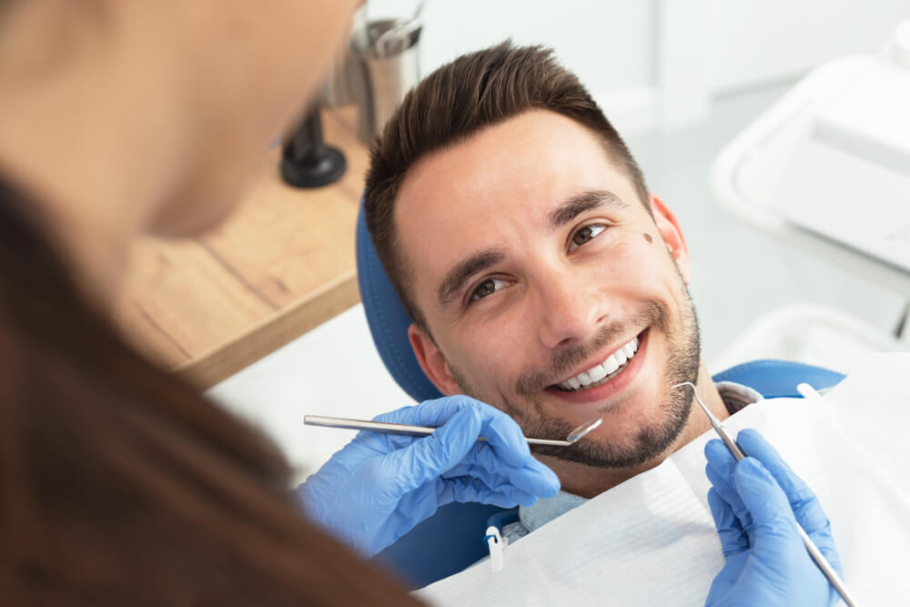 Handsome patient sitting on chair at dentist office in dental clinic.