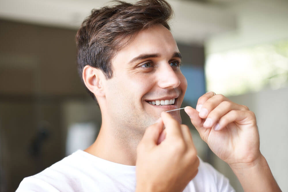 Closeup of a young man flossing.