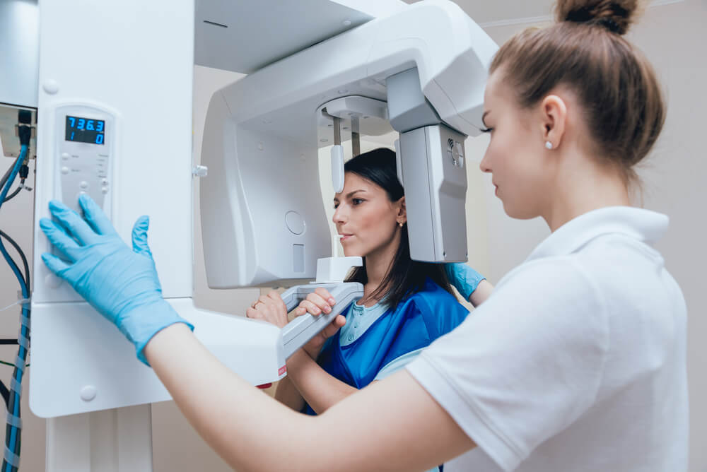 Young woman patient standing in x-ray machine.