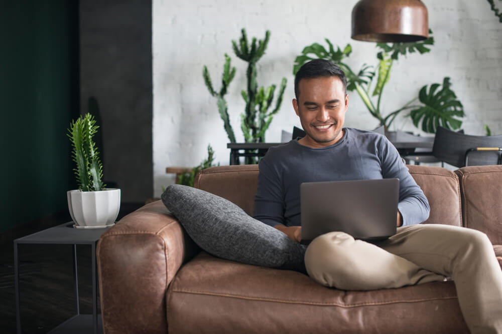 Young happy Asian man using the laptop at home.