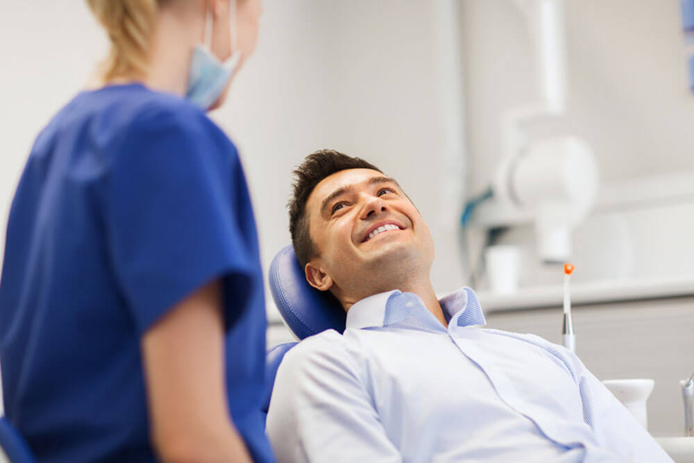 female dentist with happy male patient at clinic