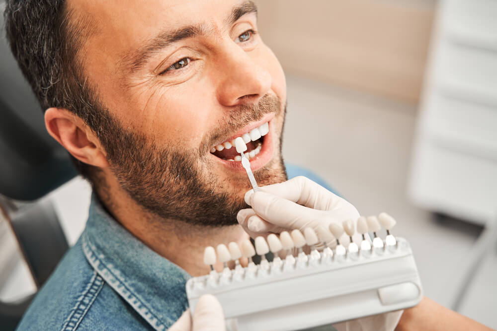 Dentist choosing color of tooth enamel in patient.