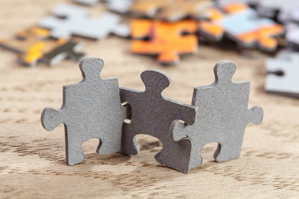 Three jigsaw puzzle pieces on a table joint together.