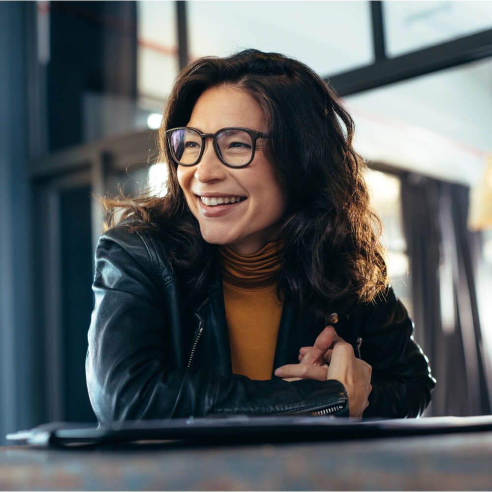 Woman sitting at the desk with laptop looking away and smiling