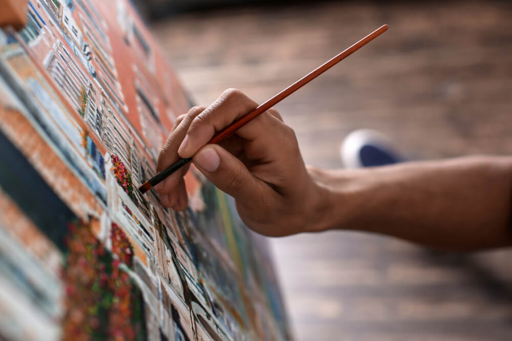 Young African-American artist painting picture in workshop