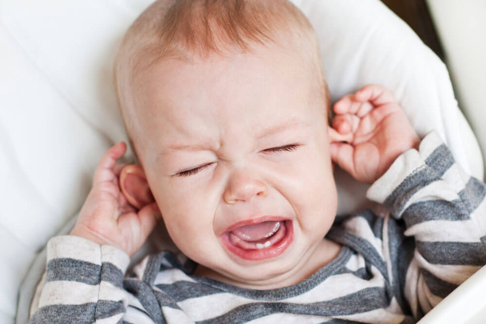 cute little boy crying and holding his ear on a white background