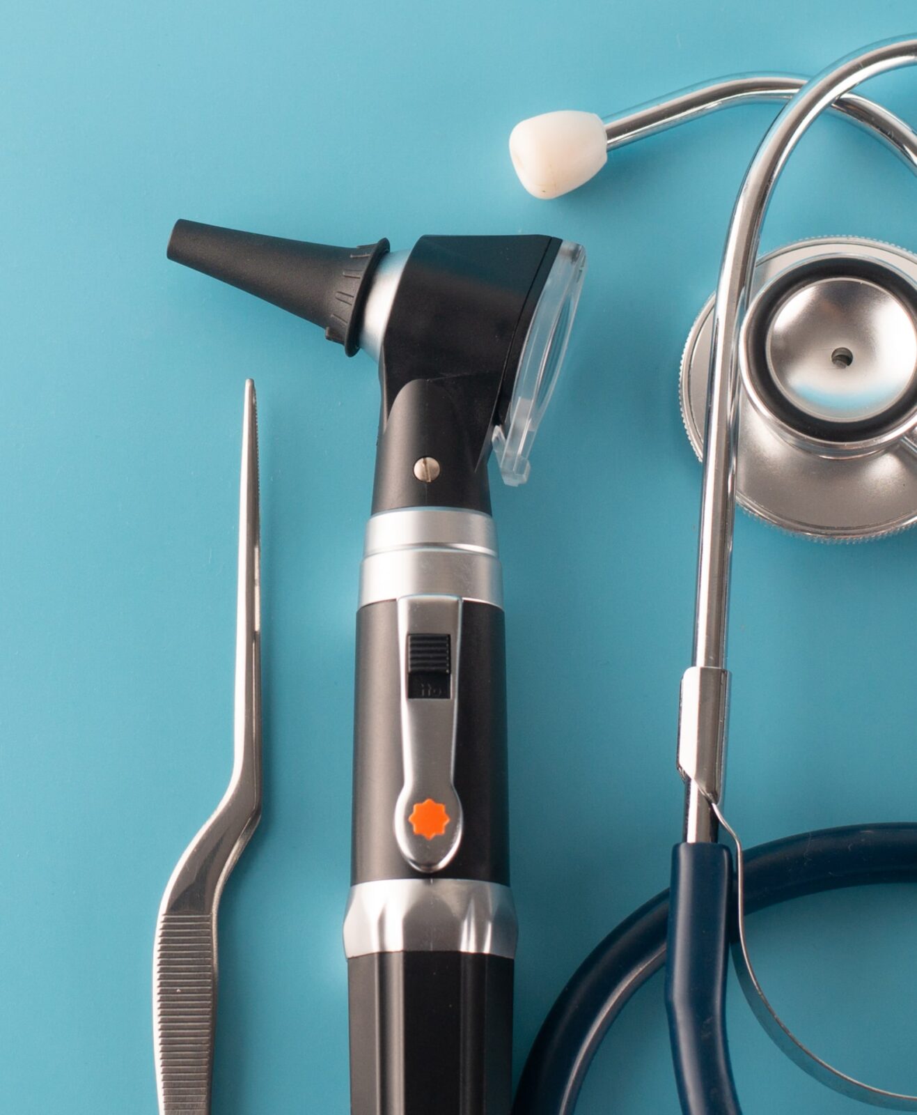 Otoscope with stethoscope on blue background.