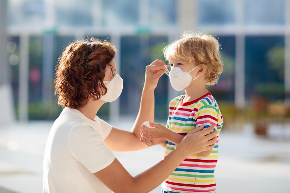 Family with kids in face mask in shopping mall or airport