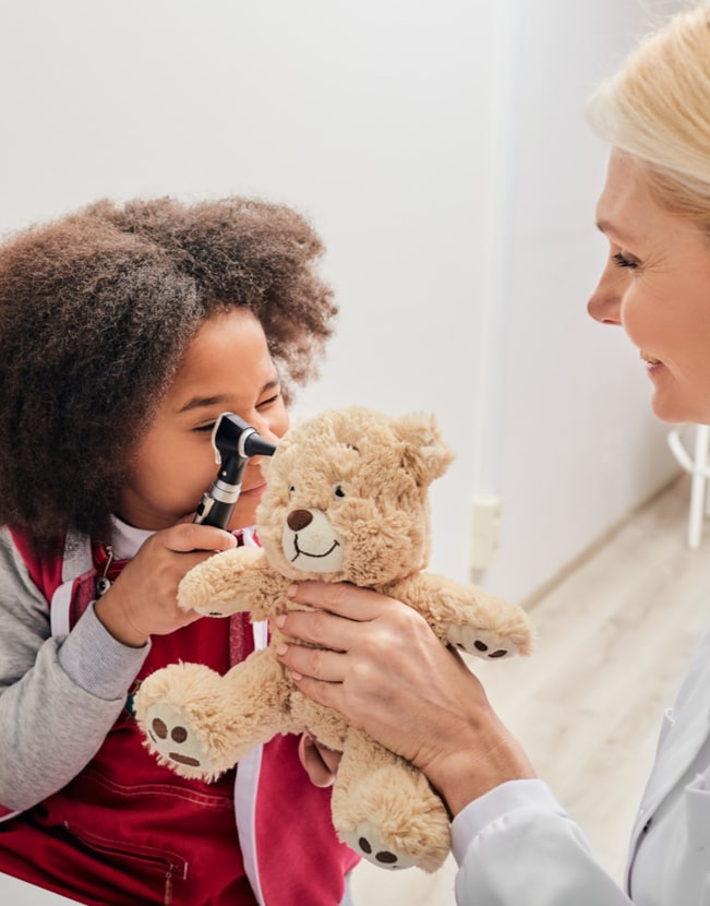 ENT doctor checking African female kid's ear using an otoscope. Hearing exam for children