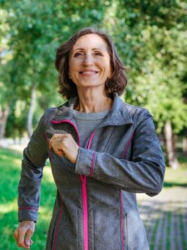 Happy mature woman wearing sports clothing jogging in the park.