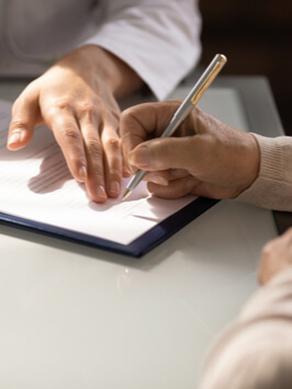 Hands of woman filling document at appointment in doctor office