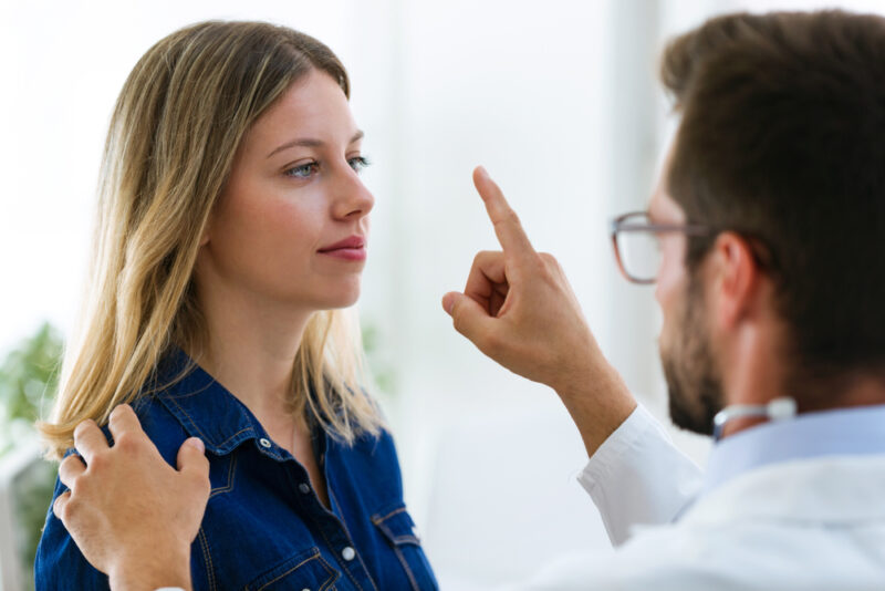 Shot of attractive male doctor ophtalmologist checking the eye vision of beautiful young woman