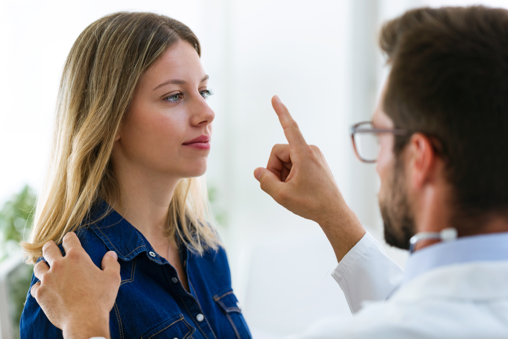 Shot of attractive male doctor ophtalmologist checking the eye vision of beautiful young woman