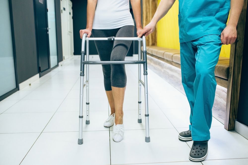 Rehabilitologist helps patient while walking