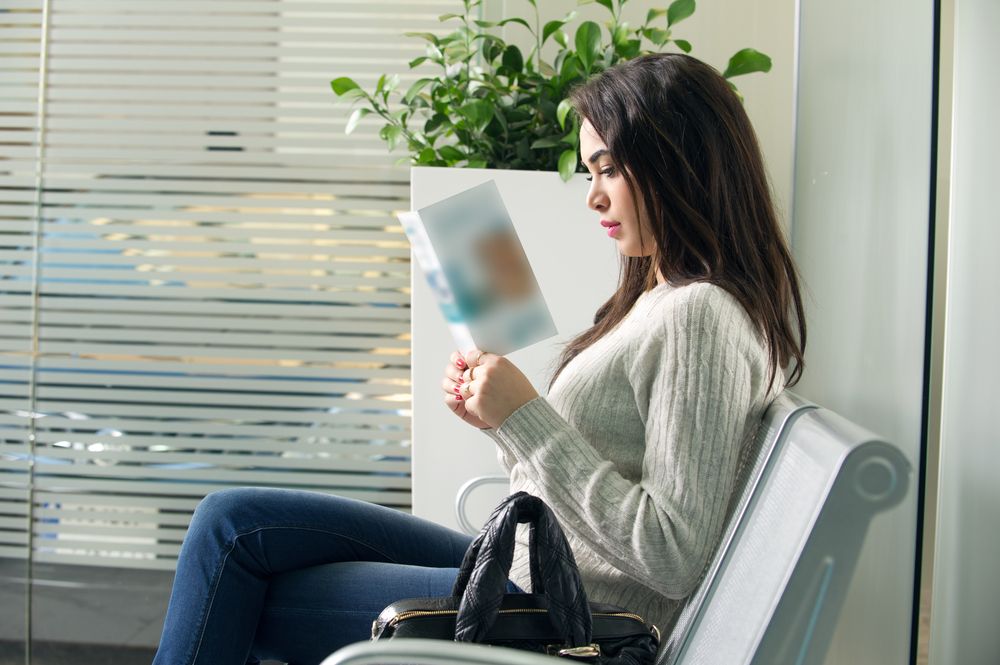 young woman reading brochure in doctor's waiting room