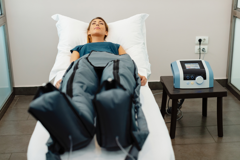 Relaxed woman enjoying in pressotherapy treatment at wellness center.