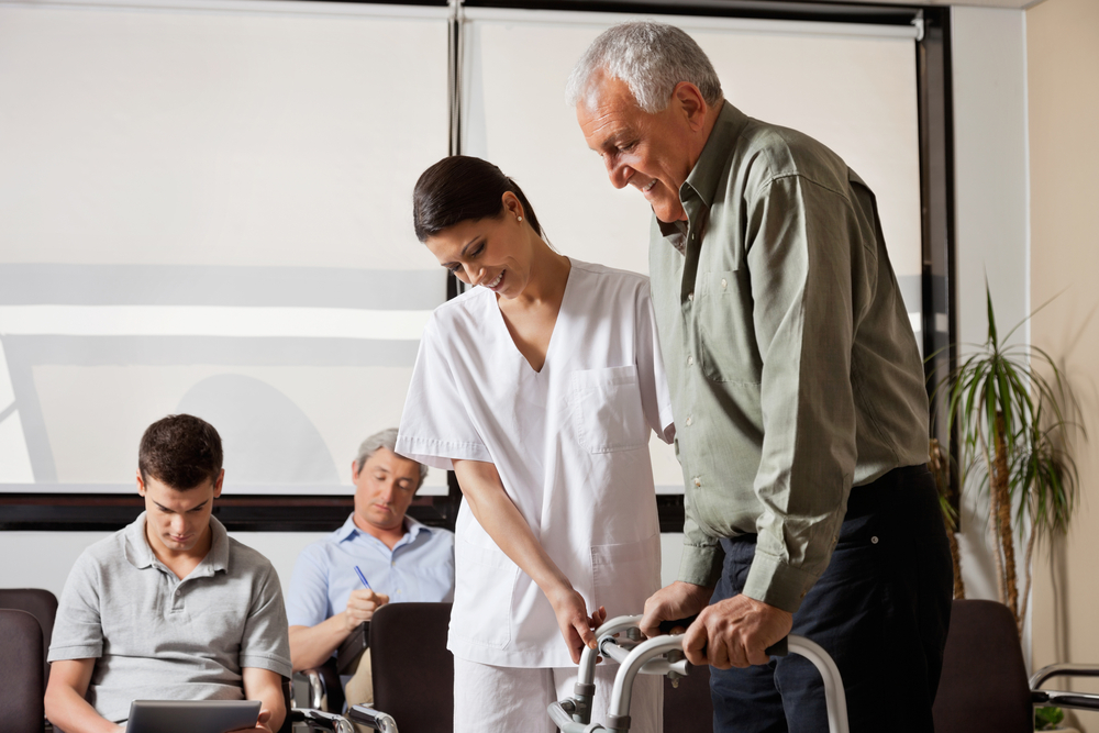 Senior man being assisted by female nurse to walk the Zimmer frame