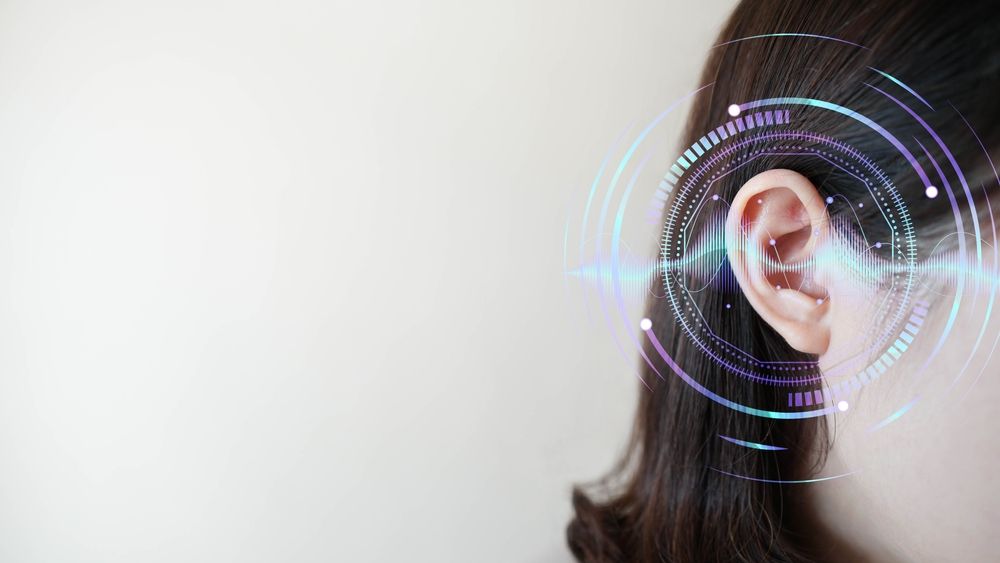 Ear of young woman with sound waves simulation technology