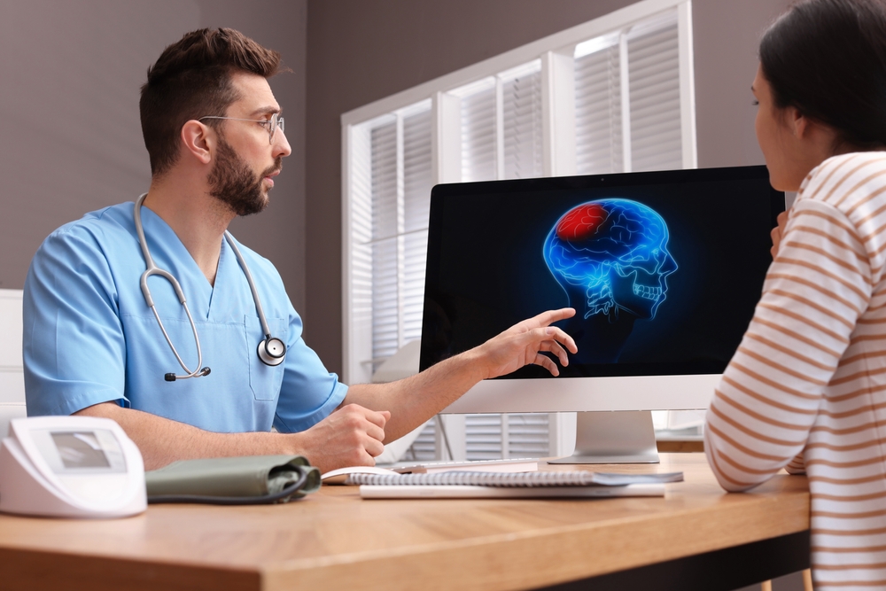 Neurologist showing brain scan to young woman in clinic