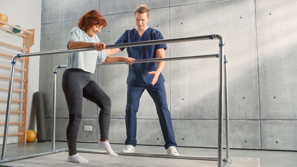 f Strong Senior Woman with Leg Injury Successfully Walks Holding Parallel Bars