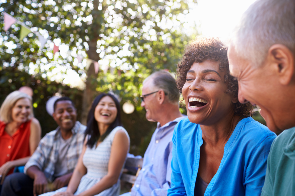 A group of people laughing, sitting outside