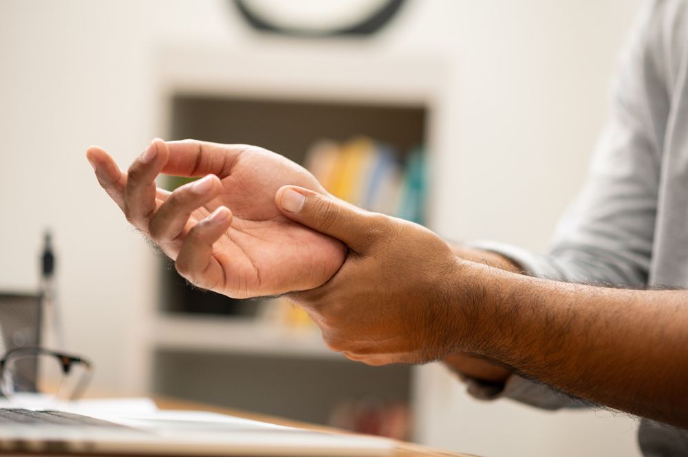 Person massaging their numb hand due to Parkinson's Disease. 
