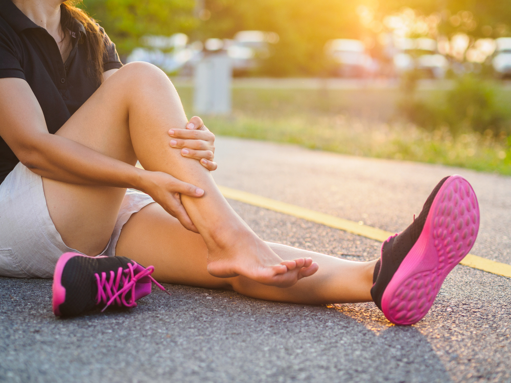 Woman sitting on the ground massaging her leg, dealing with symptoms of MS