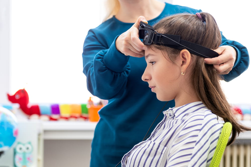 Young teenage girl and child therapist during EEG neurofeedback session. Electroencephalography concept.