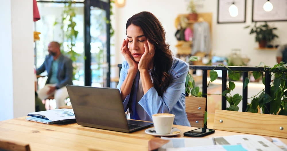 Remote work, headache and woman in cafe with stress, sick or overwork with burnout on laptop.